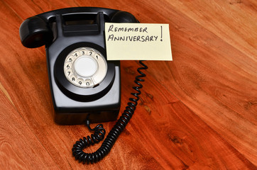 Black retro telephone with reminder note to remember anniversary