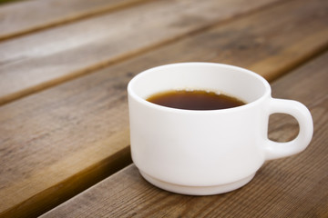 White cup of coffee on wooden table.