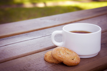 Cup of coffee with cookies on wooden table.