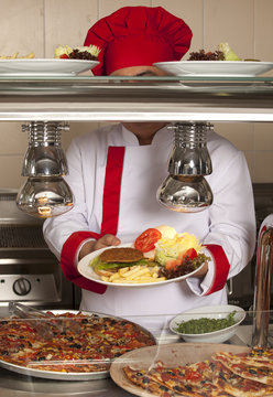 chef standing behind burger and pizza station 