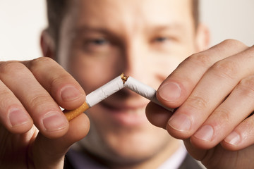smiling man with a blurred face breaks a cigarette