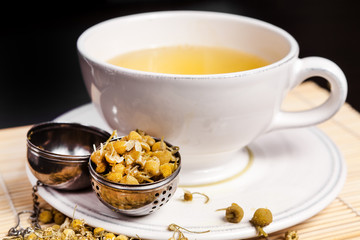 Chamomile tea in a cup of hot water with strainer 
