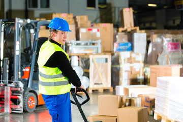 Storeman with mover at warehouse of forwarding - obrazy, fototapety, plakaty