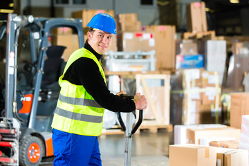 Storeman with mover at warehouse of forwarding - obrazy, fototapety, plakaty