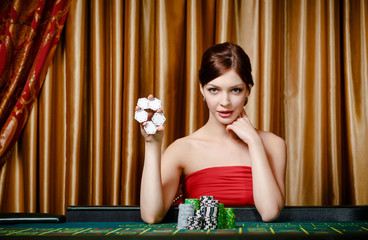 Female gambler shows chips in hand sitting at the playing table