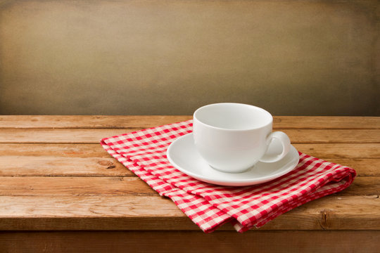 Empty coffee cup on tablecloth on wooden table