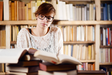 Student reading books and learning in front of a bookshelf