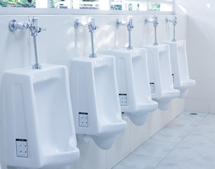 modern restroom interior with urinal row .