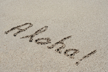 Aloha handwritten in sand on a beach