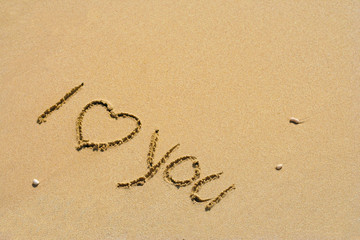 Conceptual handwritten love you text in sand