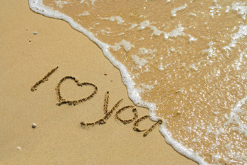 Conceptual handwritten love you text in sand