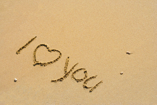 Conceptual handwritten love you text in sand