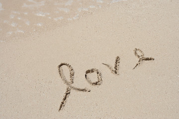 Conceptual handwritten love text in sand