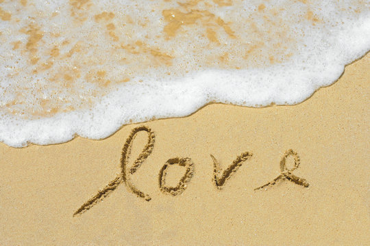 Conceptual handwritten love text in sand