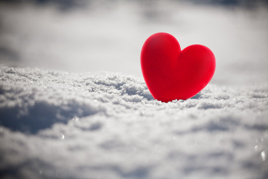 Red heart on snow, close up photo