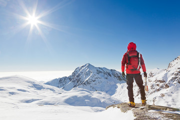 Mountaineer looking at a snowy mountain landscape - obrazy, fototapety, plakaty