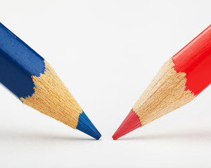 Obraz premium red and blue pencils against each other on a white paper sheet