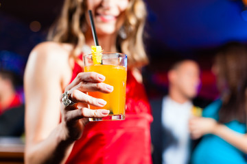 Woman with cocktail in bar or club