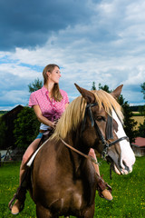 Fototapeta premium Young woman riding the horses on the meadow