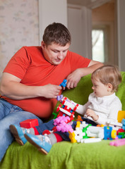 father and  three-year child plays  in home
