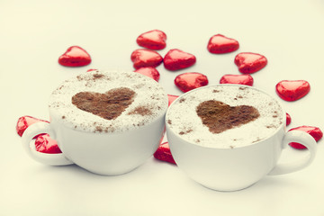 Two cup of coffee with heart symbol and candy around.