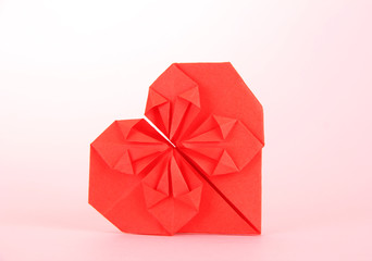 Origami paper heart on pink background.