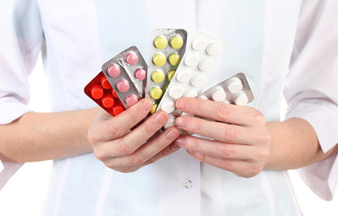 Close-up of female doctor hand holding pills, isolated on white