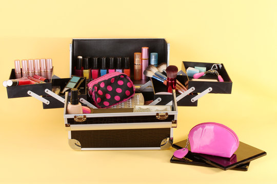 open case with cosmetics on yellow background