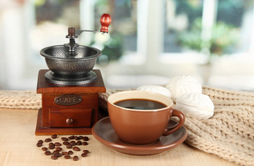 cup of coffee with scarf and coffee mill on table in room