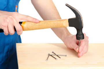 Builder hammering nails into board isolated on white