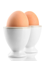 Whole boiled eggs in egg cups, isolated on white