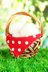 Many eggs in basket on grass on bright background