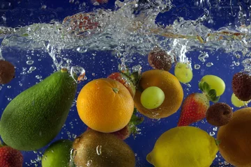 Photo sur Plexiglas Éclaboussures deau Les fruits éclaboussent dans l& 39 eau avec des bulles sur fond bleu