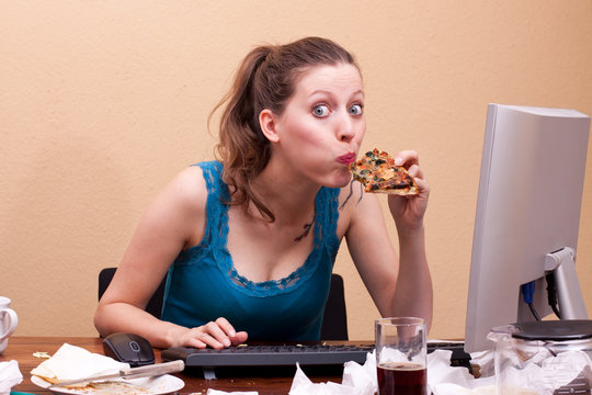 junge frau isst Pizza am Arbeitsplatz