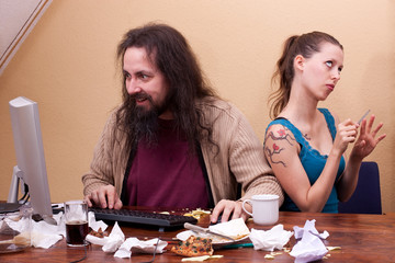 Langhaariger Nerd am Computer mit genervter schönen Frau