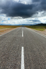 An empty desert road with dark and foreboding storm clouds