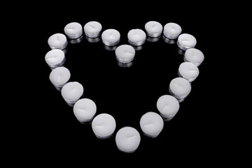 Group of white candles forming a heart  on black isolated.