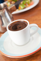 Cup of turkish coffee with salad in background