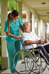 Krankenschwester redet mit Mann im Rollstuhl