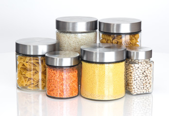Food ingredients in glass jars, on white background
