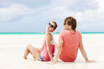 beautiful young couple sitting and having fun on beach