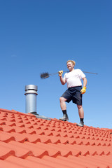 Man cleaning chimney on tiled roof