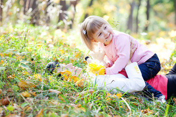 beautiful young mother and her daughter lying on the autumn leav