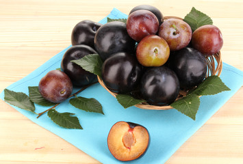 Rip plums on basket on wooden table