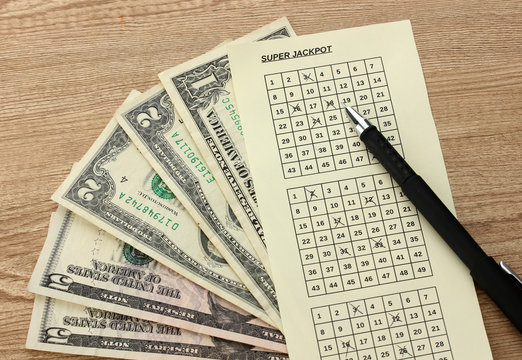 Lottery ticket with pen and money, on wooden background