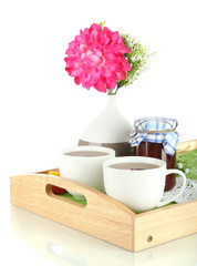 Cups of tea with flower and jam on wooden tray isolated on