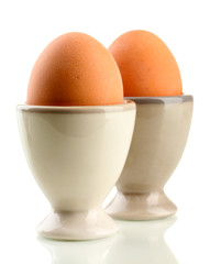 Whole boiled eggs in egg cups, isolated on white