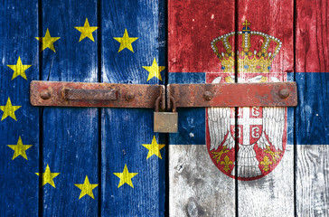 EU and Serbian flag on the background of old locked doors © borabajk