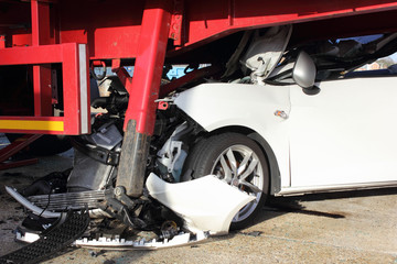 A car that has crashed into a lorry trailer causing much damage