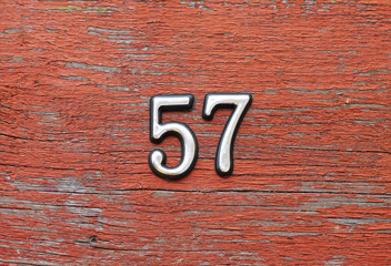 number 57 on red wooden wall, close-up